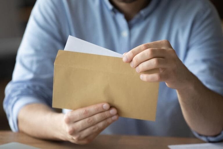 Homme assis à son bureau de travail tenant une enveloppe