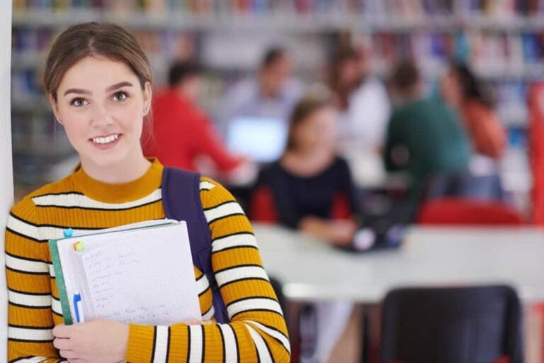 Eleve utilise un cahier et une bibliothèque scolaire