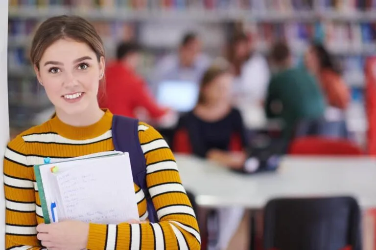 Eleve utilise un cahier et une bibliothèque scolaire