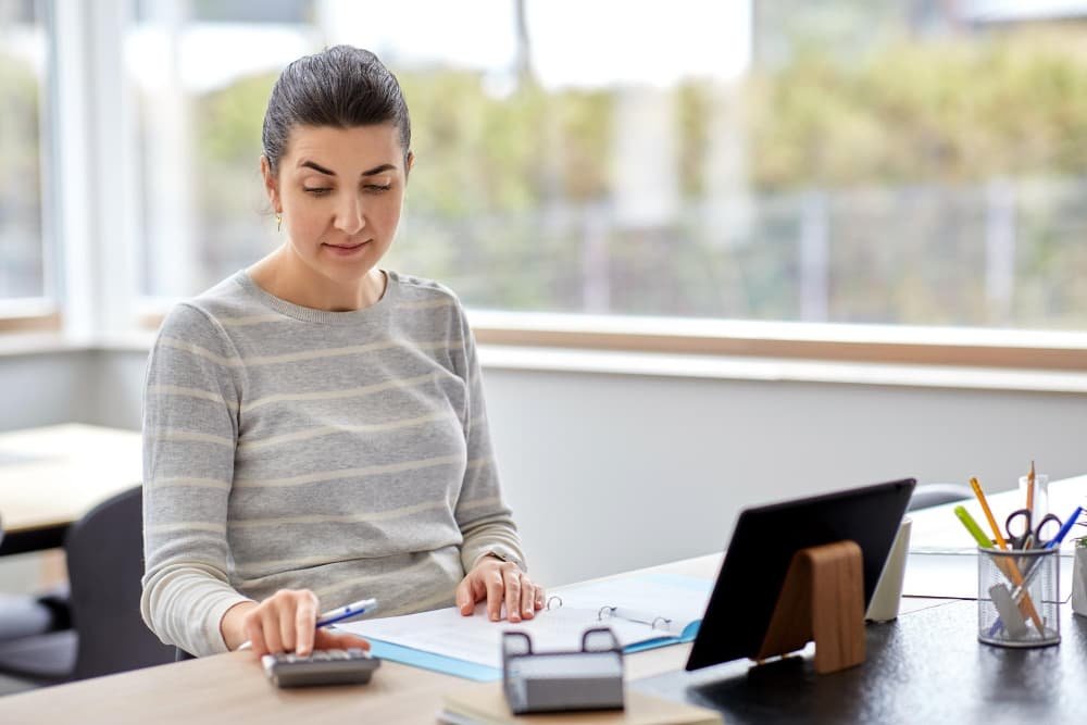 Femme avec calculatrice et papiers travaillant à la maison